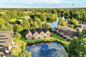 Ferienhausreihe an einem Seerosenteich mit strahlend blauem Himmel mit Natursee im Hintergrund